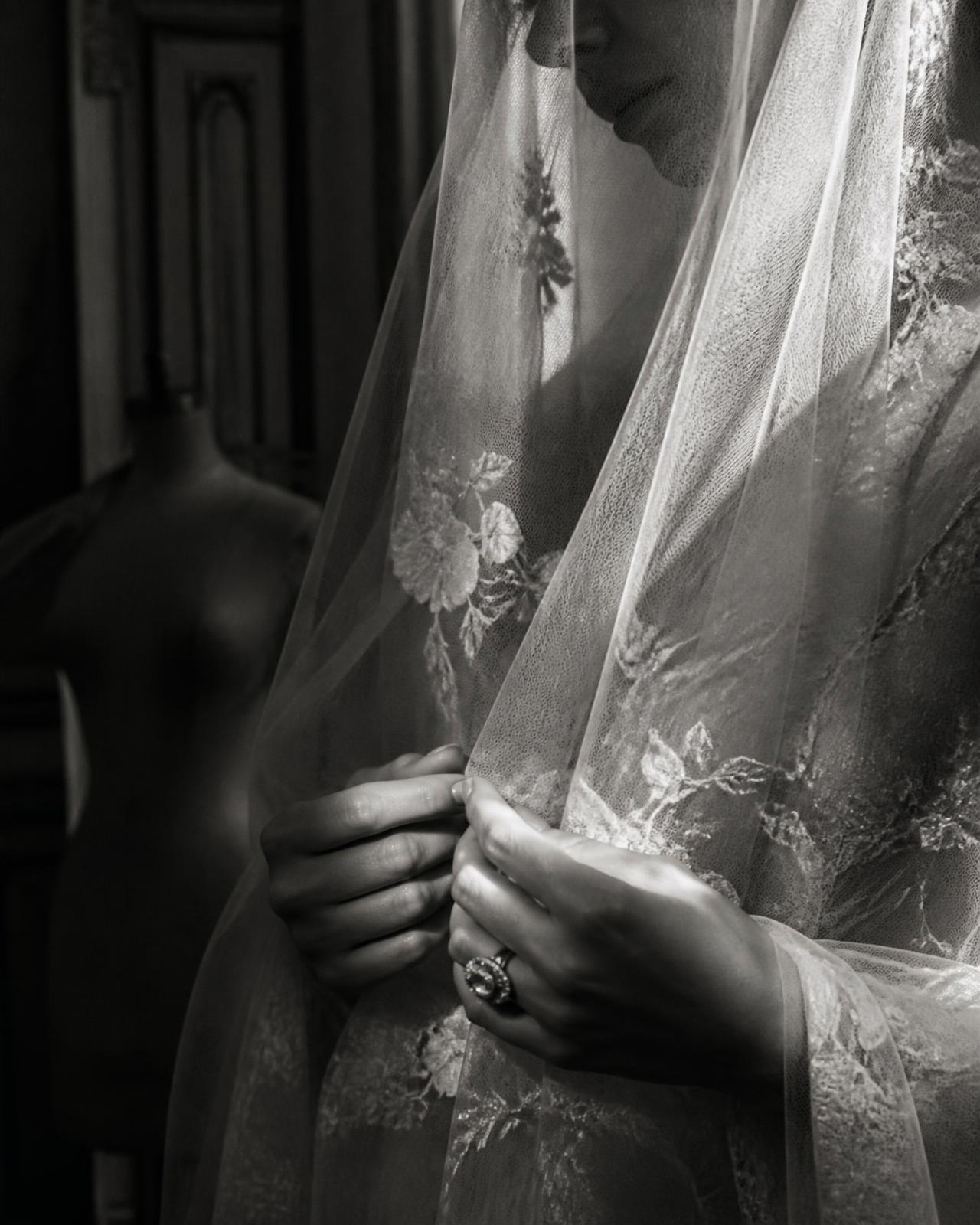 Black and white detail of a couture veil and the bride's hands with a vintage ring