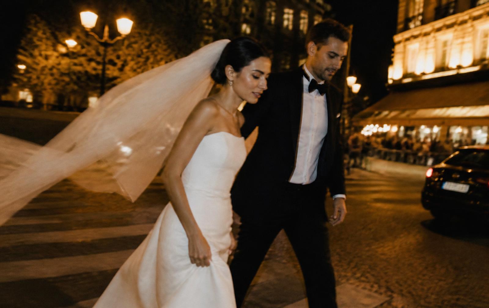 Couple walking a Parisian street at night with the veil catching the wind